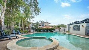 Una piscina con hidromasaje, rodeada de sillones de descanso y palmeras.