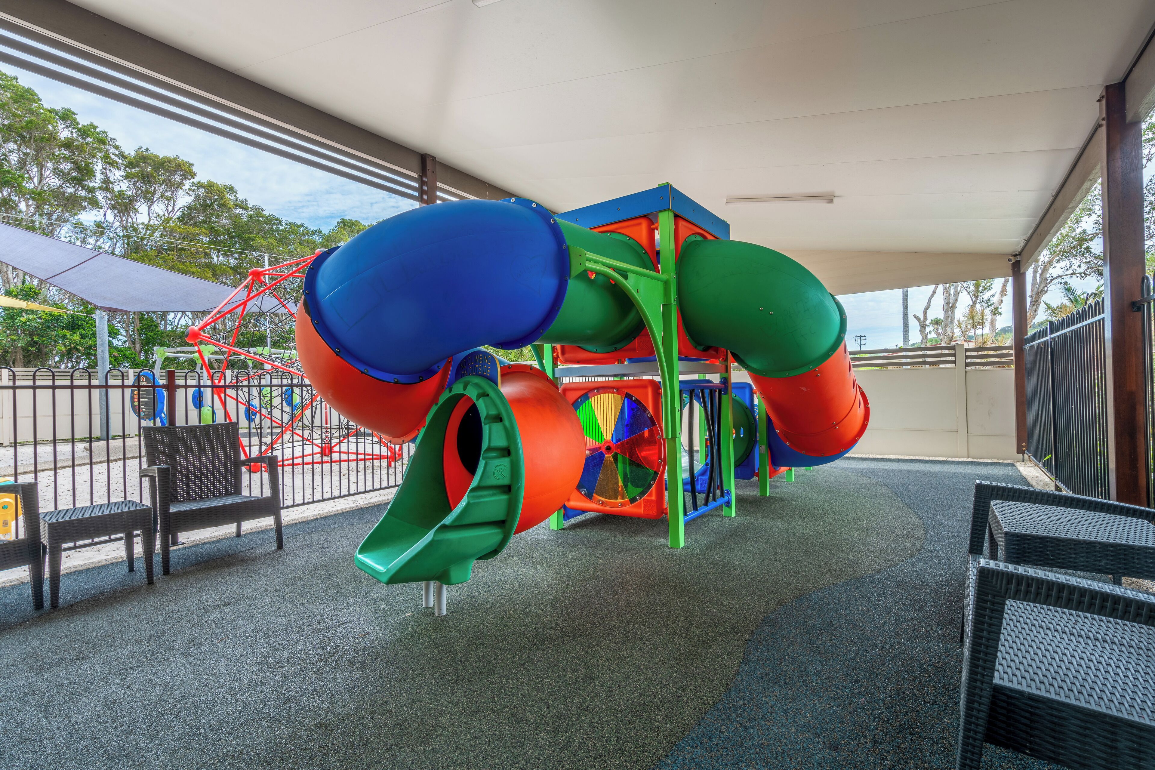 A covered play area with a slide, seating, and a view of the outdoors.