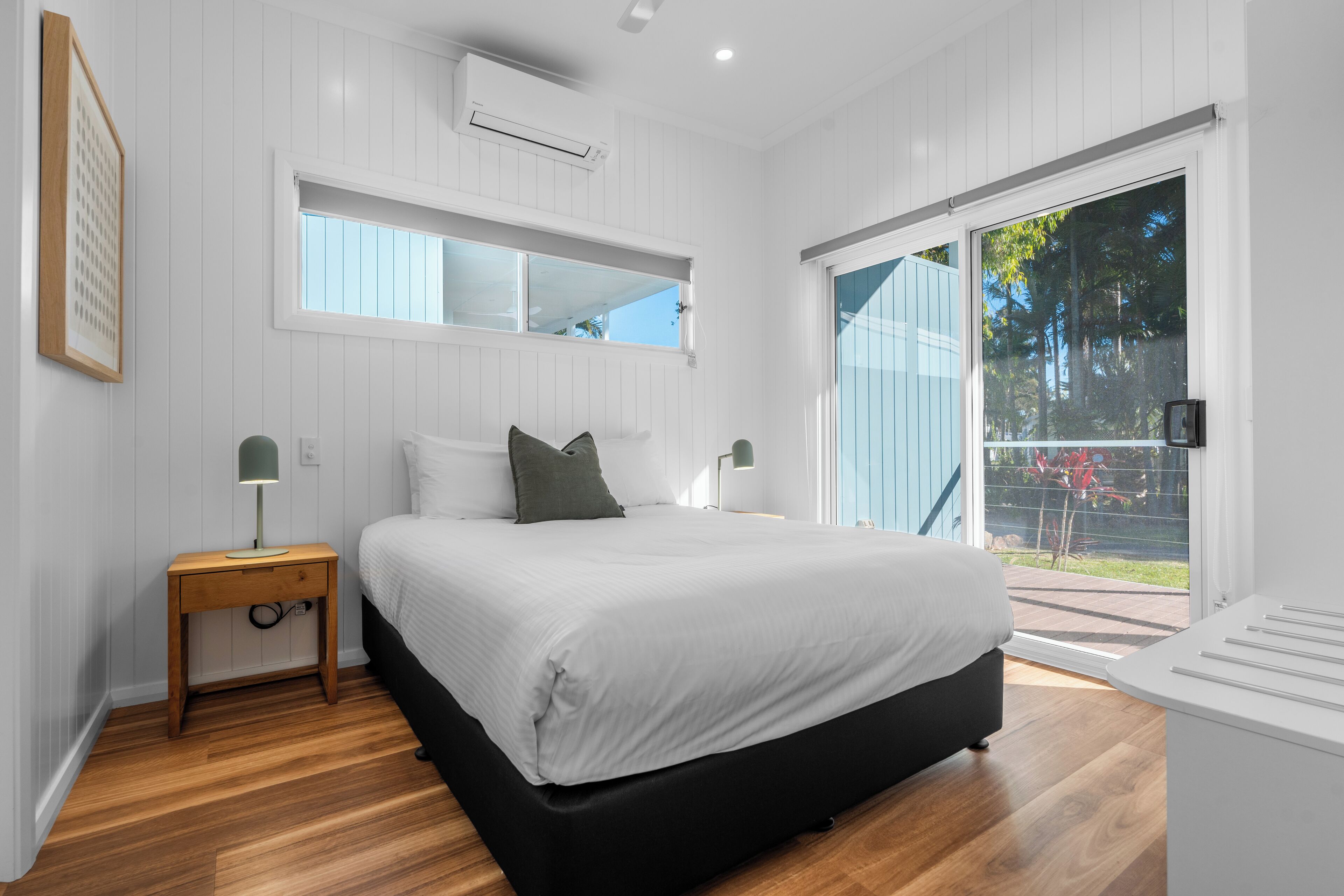 A bedroom with a bed, wooden nightstand, and a window.