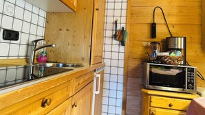 A kitchen with wooden cabinets, a stainless steel sink, a microwave, and a toaster. - Apartment Almbrünnerl 30 sqm, 1 bedroom, 1 living room/bedroom, kitchen, max. 2 p. (Ruhpolding)