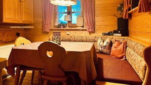 A cozy cabin interior with a wooden dining table, a bench, and a sofa. - Apartment Almbrünnerl 30 sqm, 1 bedroom, 1 living room/bedroom, kitchen, max. 2 p. (Ruhpolding)
