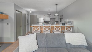 Een moderne keuken met een centraal eiland, hanglampen en een inbouwkoelkast.