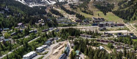 An aerial view of a mountain town with residential buildings, roads, and a ski slope.