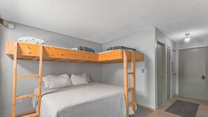 Een slaapkamer met een stapelbed, een deur en een lichtschakelaar op de muur.