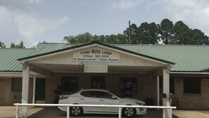 A building with a sign reading "Linder Motor Lodge" and a car parked in front. - Linder Motor Lodge (Homer)