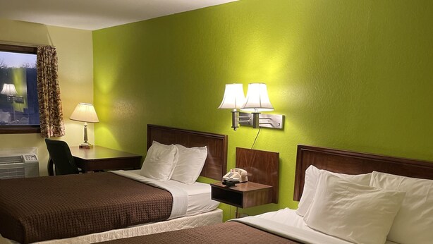 A hotel room with two beds, a desk, a chair, a lamp, and a TV. - Linder Motor Lodge (Homer)