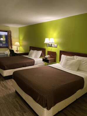 Een hotelkamer met twee bedden, een bureau, een stoel, een lamp en een televisie.