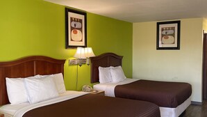 A hotel room with two beds, green walls, wooden headboards, and a framed picture on the wall. - Linder Motor Lodge (Homer)