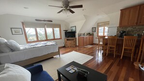 Un loft spacieux comprenant un grand lit, un coin repas, une cuisine et un ventilateur de plafond.