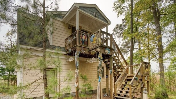 Une maison à deux étages avec un balcon et un escalier en bois.