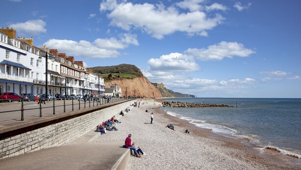 A coastal promenade with a pebble beach, a stone wall, and buildings along the shore. - Heart of Sidmouth - Pet Friendly - Free WiFi (Sidmouth)
