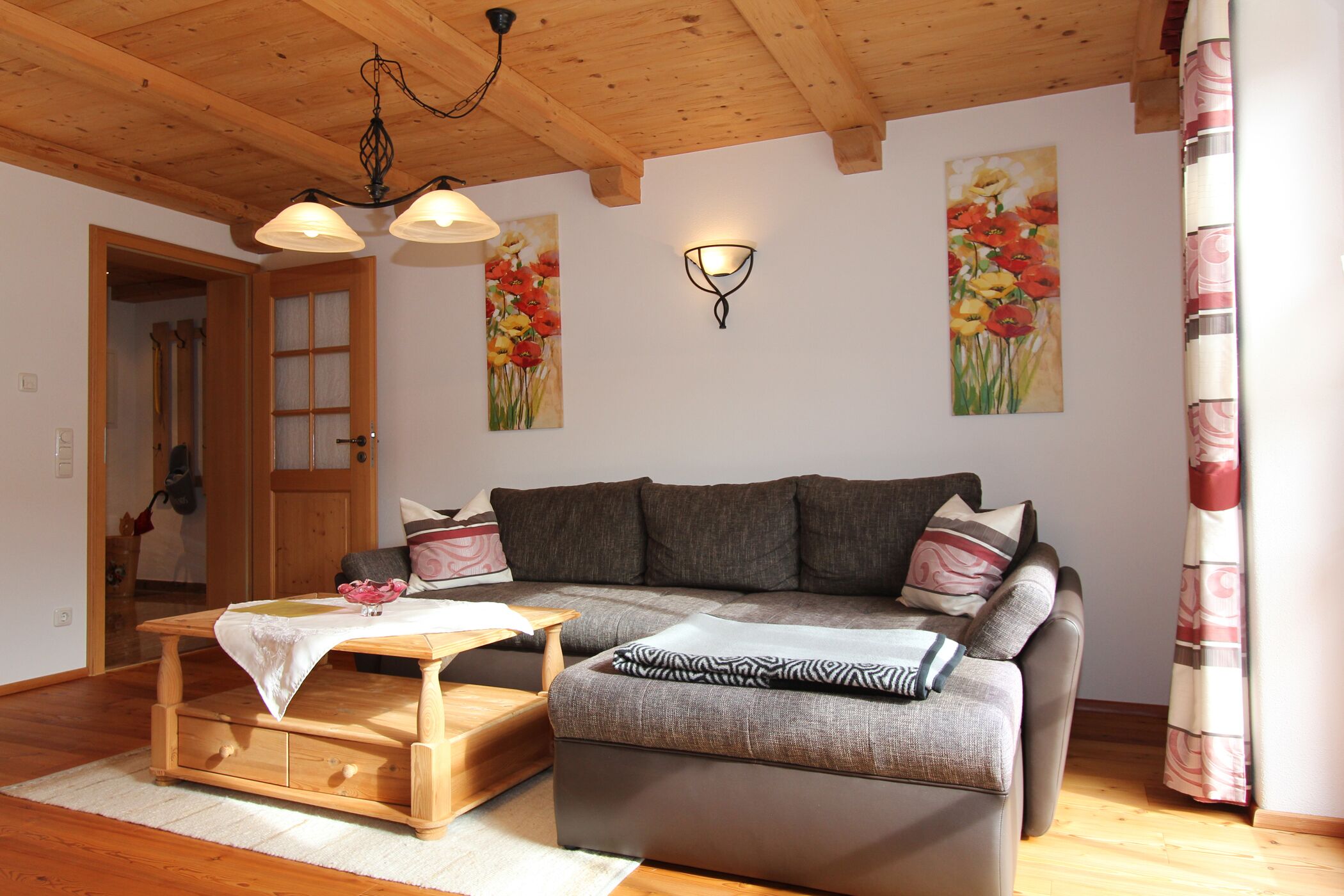 Ein gemütliches Wohnzimmer mit einer Couch, einem Holztisch und einem Blumenbild an der Wand.
