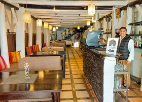 Un restaurante con zona de bar, mesas y sillas, y un mostrador de recepción.