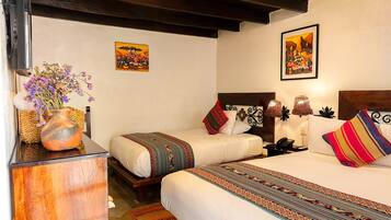 A hotel room with two beds, a wooden nightstand, a vase with flowers, and two wall-mounted paintings.