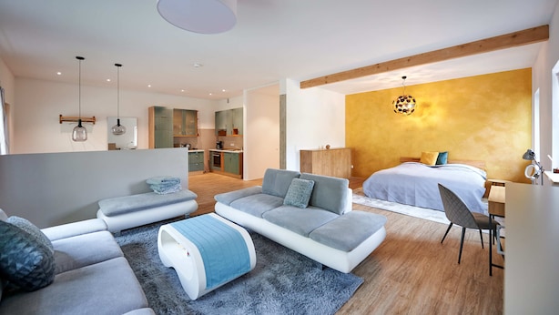 A modern bedroom with a large bed, a sofa, and a desk area. - Sicado-Loft vacation apartment 75 sqm, open-plan living room and bedroom, terrace (Aschau im Chiemgau)