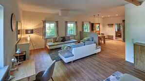 A modern living room with a sofa, a desk, and a dining area. - Sicado-Loft vacation apartment 75 sqm, open-plan living room and bedroom, terrace (Aschau im Chiemgau)