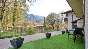 A patio with artificial grass, two planters, a chair, and a table. - Sicado-Loft vacation apartment 75 sqm, open-plan living room and bedroom, terrace (Aschau im Chiemgau)