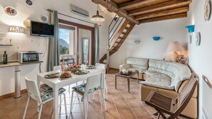 A cozy kitchen with a dining area, a sofa, and a staircase leading to another level.