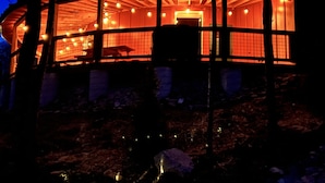 A wooden cabin with a curved roof, multiple windows, and interior lighting.
