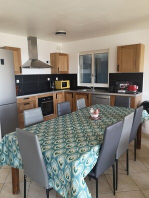 A compact kitchen with wooden cabinets, a microwave, a stove, and a dining table with chairs.