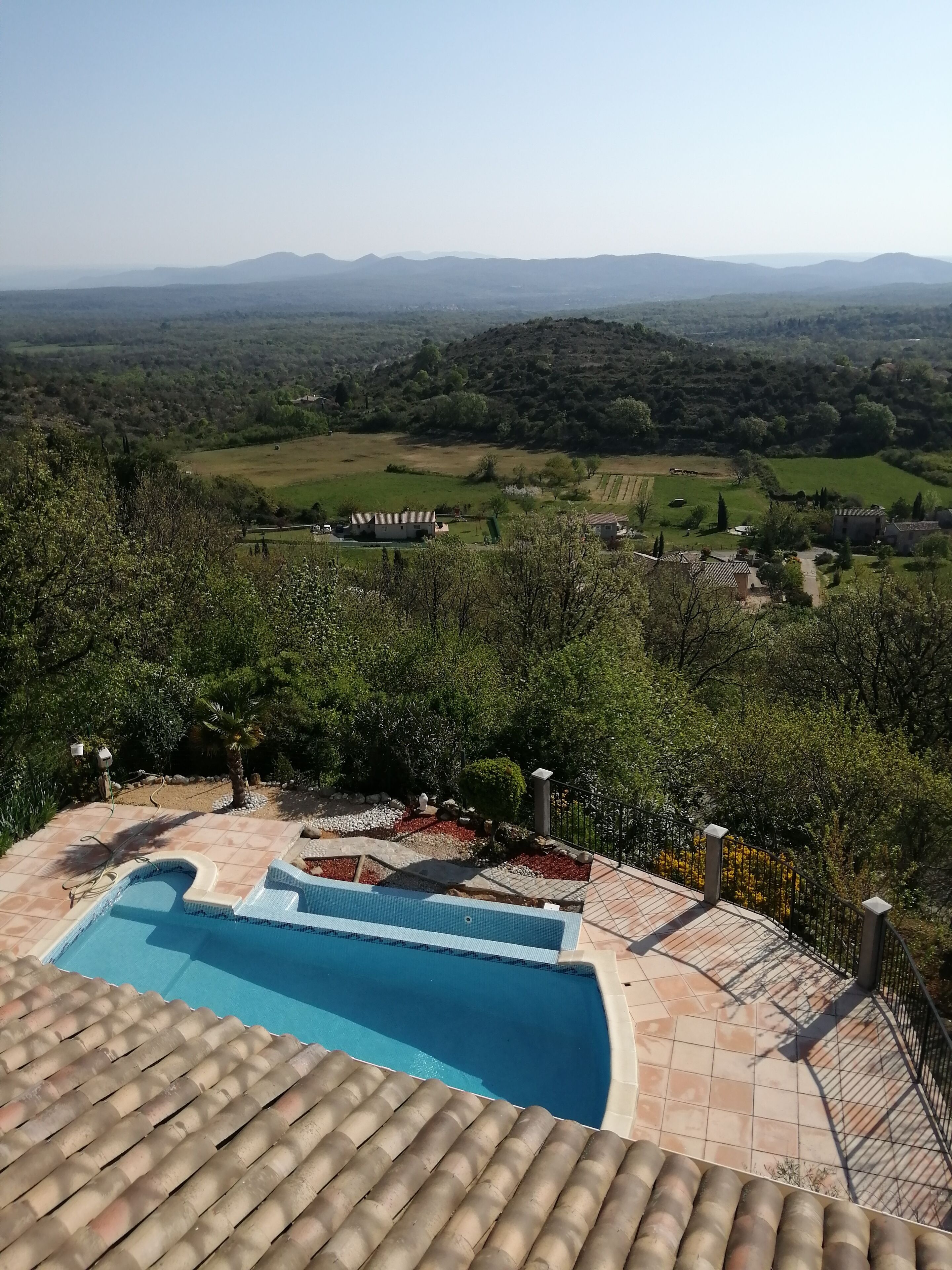 Un espace piscine offrant une vue sur un paysage rural, avec des champs et des collines à l’horizon.