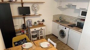 Une cuisine compacte  équipée d’un lave-linge, d’un four à micro-ondes et d’un coin repas avec des assiettes et des couverts.