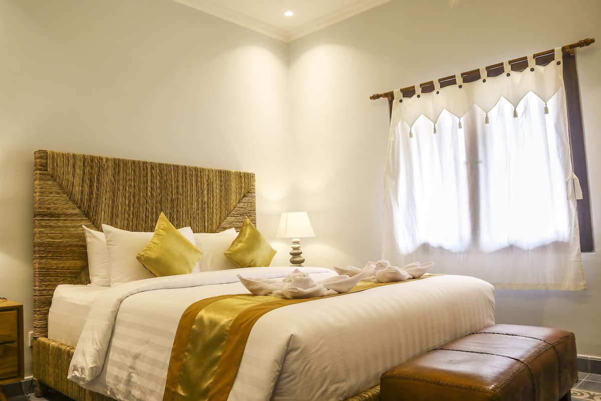 A neatly arranged bedroom with a bed, bedside tables, and a window with curtains.