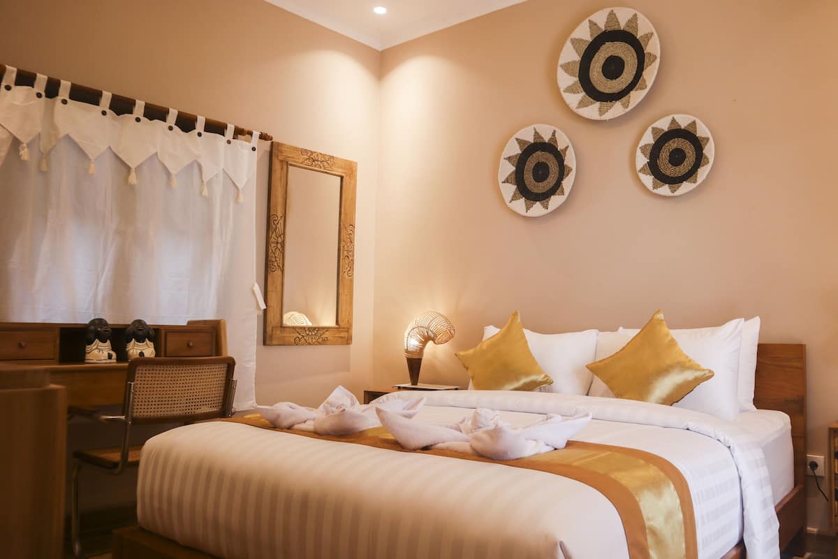 A hotel room with a bed, bedside tables, a mirror, and decorative wall art.