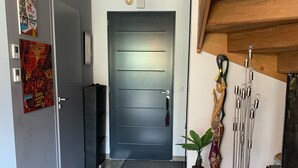 Una sala de estar moderna con una puerta gris, un sofá blanco, un televisor y una escultura decorativa.