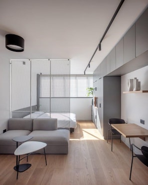 Un espacio habitable moderno y minimalista con un sofá, una pequeña mesa y una zona de comedor.