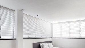 A modern bedroom with a grey sofa, a white coffee table, and a bed with white bedding. - DeBlox living - Ben Avigdor (Tel Aviv)