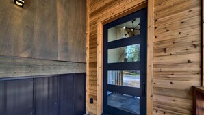 Fachada de madera con puerta de vidrio de marco negro y un pequeño porche.