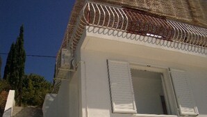 Ein weißes Gebäude mit einer Treppe, die zu einer Tür mit Fensterläden führt.