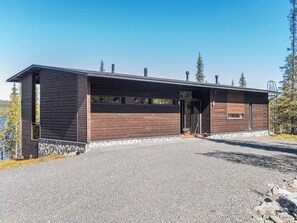 A modern building with a sloped roof, large windows, and a stone foundation. - Holy lake rantasauna by Interhome (Kuusamo)