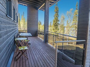 A wooden deck with a table and chairs, overlooking a forested area. - Holy lake rantasauna by Interhome (Kuusamo)