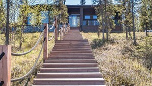 Una escalera de madera que lleva a un edificio moderno rodeado de árboles.
