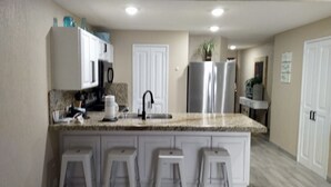 A kitchen with a granite countertop, white cabinets, a stainless steel refrigerator, and a sink. - FULLY BEACHFRONT CONDO WITH AMAZING OCEAN VIEWS (Puerto Peñasco)