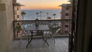 A balcony with a table and chairs, overlooking a beach and ocean. - FULLY BEACHFRONT CONDO WITH AMAZING OCEAN VIEWS (Puerto Peñasco)