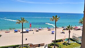A beach with palm trees, umbrellas, and people. - FULLY BEACHFRONT CONDO WITH AMAZING OCEAN VIEWS (Puerto Peñasco)