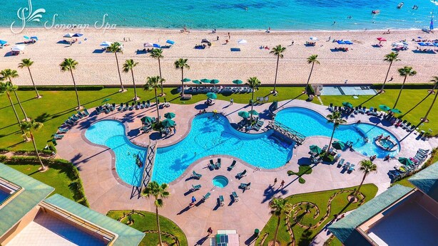 A resort with a large pool area, beach access, and palm trees. - FULLY BEACHFRONT CONDO WITH AMAZING OCEAN VIEWS (Puerto Peñasco)