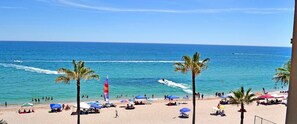Una playa con palmeras, sombrillas y gente.