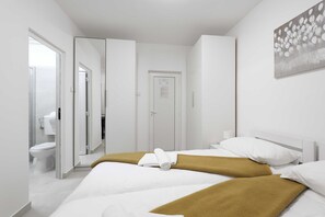 A hotel room with a bed, a bathroom, and a door.