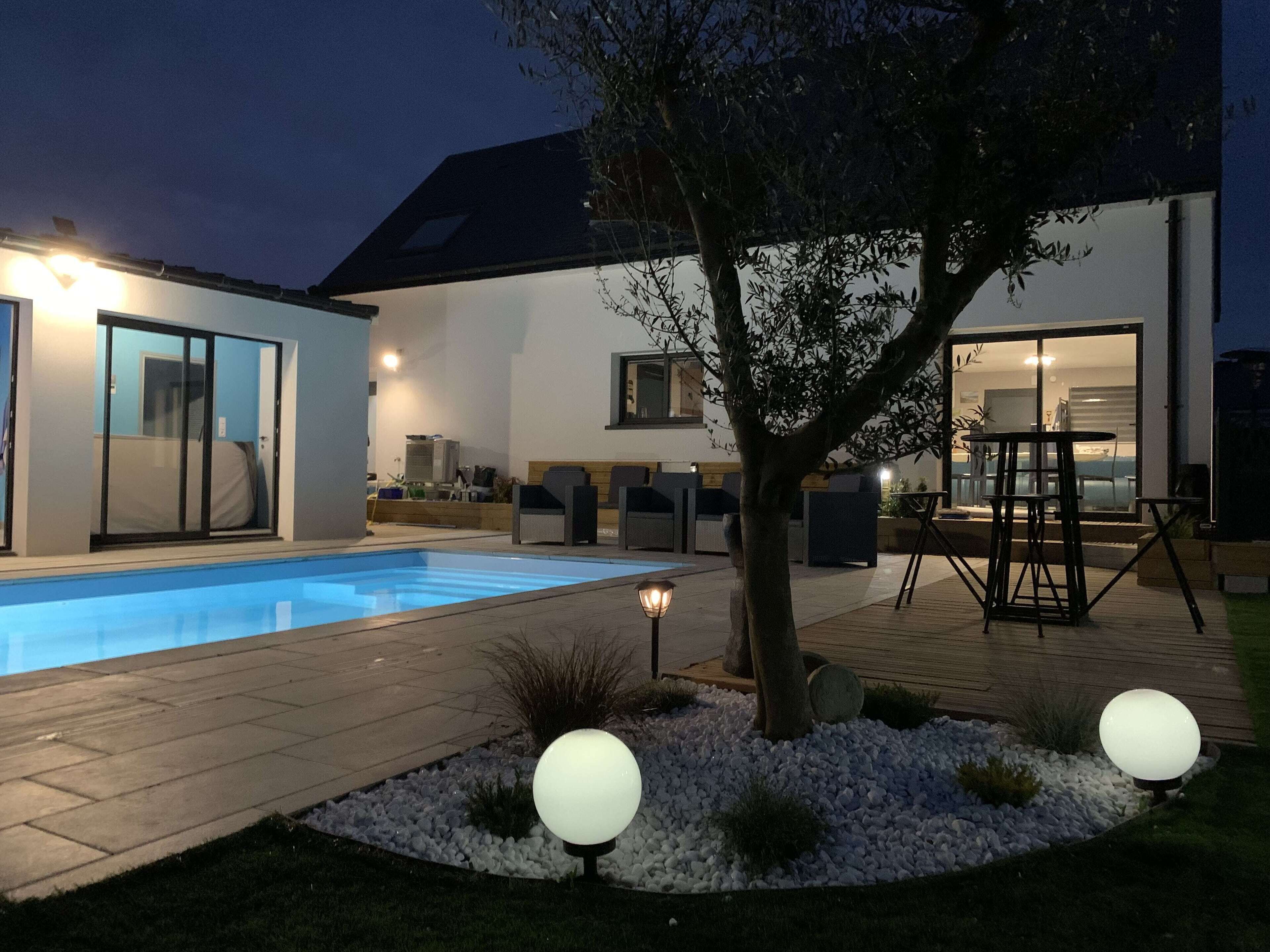 Uma casa moderna com piscina, área de estar externa e um pátio bem iluminado.