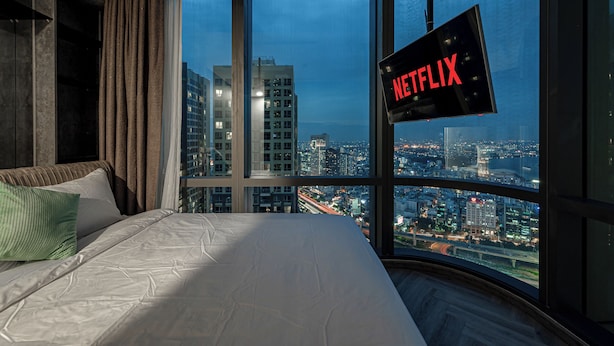 A bedroom with a large window, a bed, and a wall-mounted TV displaying the Netflix logo. - Landmark 81 Serviced Residences (Ho Chi Minh City)