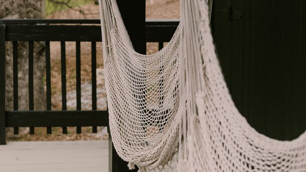 A hammock hanging on a wooden porch with a view of trees in the background. - The Base Cabin A Frame - Your Gateway to Yosemite, Relaxation and Chill Vibes (Groveland)
