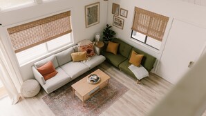 A living room with a sofa, a coffee table, and a patterned rug. - The Base Cabin A Frame - Your Gateway to Yosemite, Relaxation and Chill Vibes (Groveland)