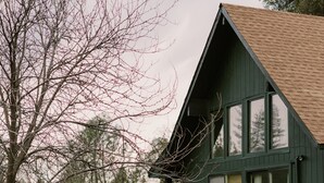 A two-story wooden house with a dark green exterior, a brown roof, and a black railing around the deck. - The Base Cabin A Frame - Your Gateway to Yosemite, Relaxation and Chill Vibes (Groveland)