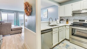 A modern kitchen with white cabinets, a dishwasher, and a stainless steel oven. - Kure Beach Condo w/ Panoramic Ocean Views! (Kure Beach)