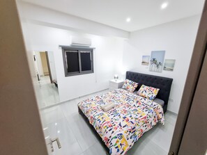 Ein Schlafzimmer mit Bett, Fenster, Nachttisch und Wandbildern.