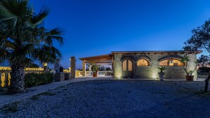 Un edificio con fachada de piedra, ventanas arqueadas y un patio cubierto.